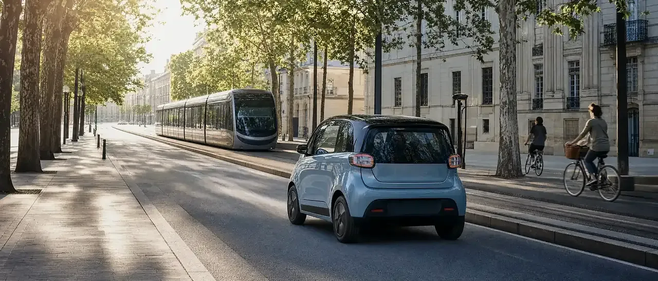 Petite voiture électrique, classée Crit'Air 0, dans une rue de centre-ville près du tramway