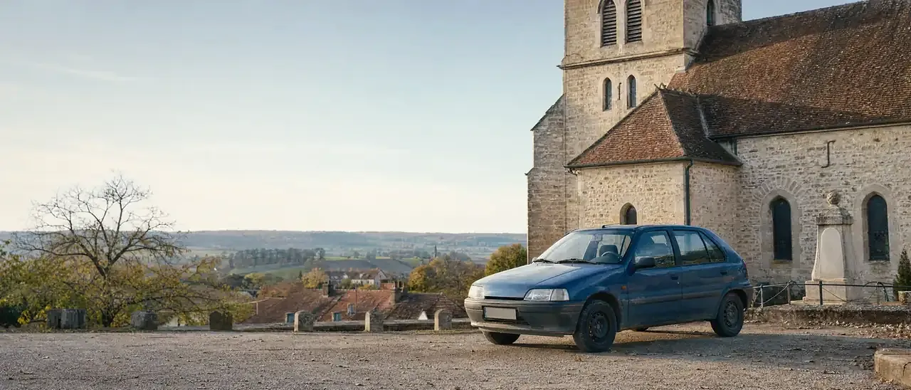 Voiture diesel des années 1990, classée Crit'Air 5, garée près d'une église de village