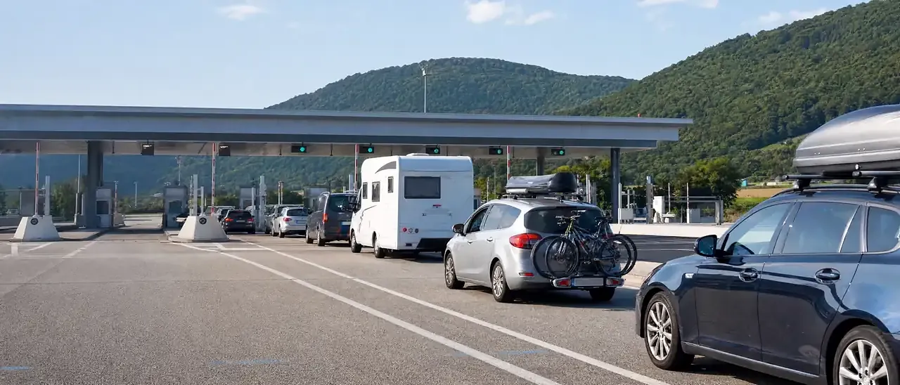 Voitures de vacanciers à un péage d'autoroute en France, avec coffres de toit et porte-vélos