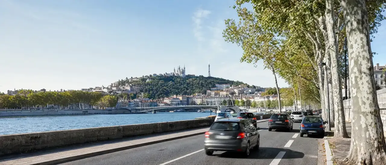 Voitures sur les quais du Rhône à Lyon, la colline de Fourvière au fond
