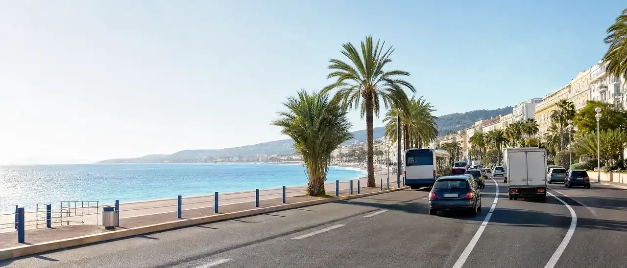 Circulation sur la promenade des Anglais à Nice, avec un bus et un camion au bord de la mer